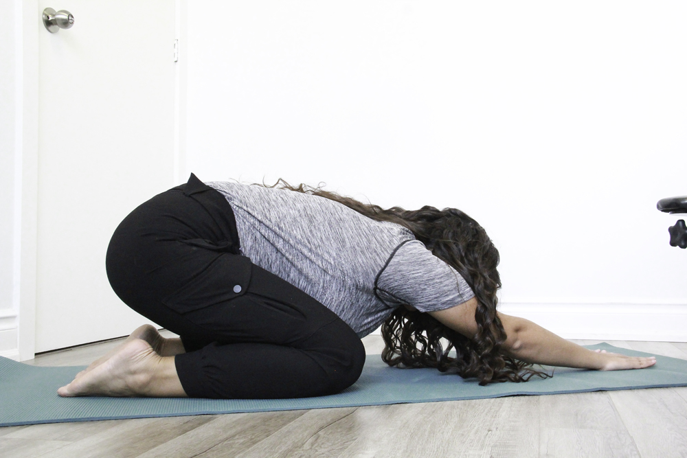 Patient performing child’s pose stretch on yoga mat for spinal mobility at DC Chiropractic Markham