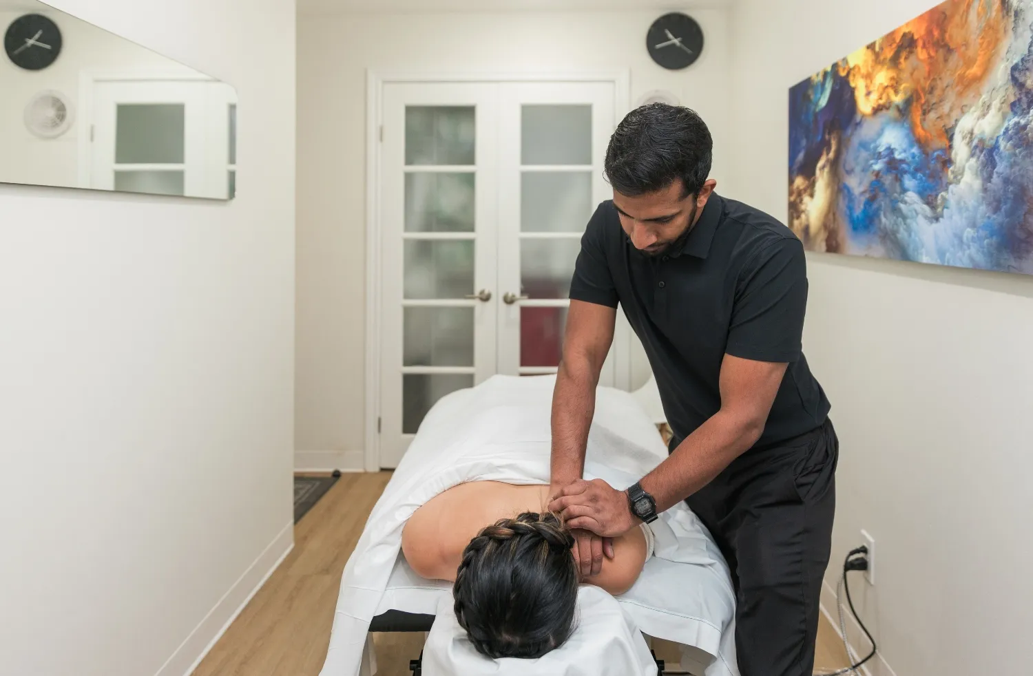 Chiropractor performing manual therapy on a patient's upper back in a treatment room at DC Chiropractic Markham